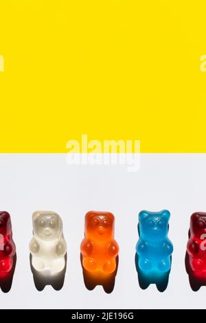 Nahaufnahme der bunten Jelly Bears auf der weißen und gelben Oberfläche Stockfoto