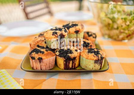 Hausgemachte süße leckere Chip-Muffins mit Beerenbeeren auf dem Teller auf hellem Hintergrund. Stockfoto
