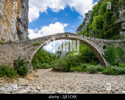 Die Brücke von Kokoros oder Noutsos wölbt sich anmutig über das je nach Saison trockene Flussbett in der oberen Vikos-Schlucht in Zagori Griechenland Stockfoto