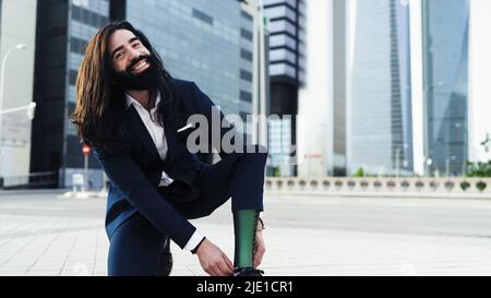 Ein junger Mann mit Behinderung, der seine Beinprothese vor dem Büro anpasst Stockfoto