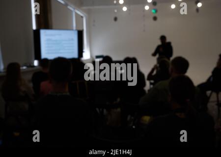 Verschwommener Hintergrund der Geschäftskonferenz, ein Mann auf der Bühne, Präsentation des Projekts, öffentlicher Vortrag. Hochwertige Fotos Stockfoto