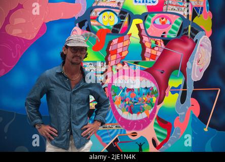 Malaga, Spanien. 24.. Juni 2022. Der deutsche Künstler Erik Parker wird bei der Eröffnung der Ausstellung „Easy Freedom“ im Contemporary Art Center für die Medien posiert. Diese Schau, die als die wichtigste Ausstellung des Künstlers gilt und Einfluss auf seine US-Subkultur hat, zeigt fast 40 Werke und Gemälde, die durch gesättigte und fluoreszierende Farben gekennzeichnet sind. Erik Parker, ein Künstler aus New York, kombiniert verschiedene Stile, die die Ästhetik der Psychedelie darstellen. Die Ausstellung läuft ab 24.. Juni bis 28.. August, (Kreditbild: © Jesus Merida/SOPA Images via ZUMA Press Wire) Stockfoto