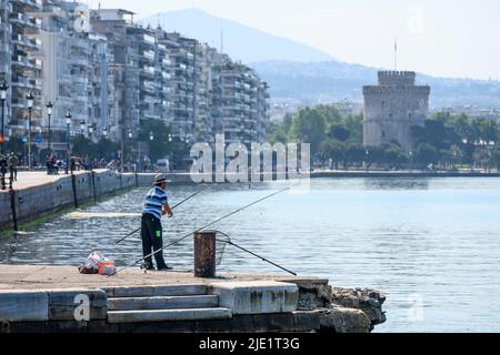Ein Fischer am Ufer von Thessaloniki mit Nikis Avenue und dem weißen Turm im Hintergrund, Mazedonien, Nordgriechenland Stockfoto
