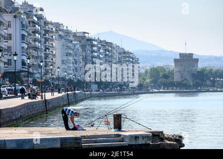 Ein Fischer am Ufer von Thessaloniki mit Nikis Avenue und dem weißen Turm im Hintergrund, Mazedonien, Nordgriechenland Stockfoto