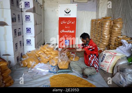 23. Juni 2022, Peshawar, khyber pakhtunkhwa, Pakistan: Mitarbeiter der Alkhidmat-Stiftung verladen Hilfsgüter auf Lieferwagen, um nach Chamkani nach afghanischen Erdbebenopfern zu versenden. Mehr als 1.000 Menschen wurden getötet und mehr als 1.500 weitere verletzt, nachdem ein Erdbeben der Stärke 5,9 vor Sonnenaufgang am 22. Juni Ostafghanistan getroffen hatte, berichtete die staatliche afghanische Nachrichtenagentur Bakhtar. Nach Angaben der Behörden dürfte die Zahl der Todesopfer steigen. (Bild: © Hussain Ali/Pacific Press via ZUMA Press Wire) Stockfoto