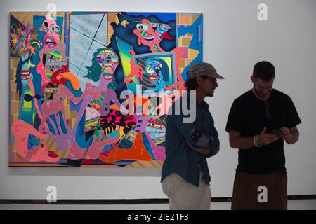 24. Juni 2022, Malaga, Spanien: Ein Gemälde wird gesehen, als der deutsche Künstler Erik Parker (C) mit einem Mann während der Eröffnung der Ausstellung "Easy Freedom" im Contemporary Art Center chattet. Diese Schau, die als die wichtigste Ausstellung des Künstlers gilt und Einfluss auf seine US-Subkultur hat, zeigt fast 40 Werke und Gemälde, die durch gesättigte und fluoreszierende Farben gekennzeichnet sind. Erik Parker, ein Künstler aus New York, kombiniert verschiedene Stile, die die Ästhetik der Psychedelie darstellen. Die Ausstellung läuft ab 24.. Juni bis 28.. August, (Bildquelle: © Jesus Merida/SOPA Bilder via ZUMA Press Wir Stockfoto