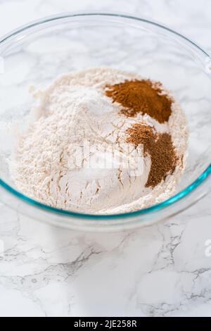 Mischen von trockenen Zutaten in einer großen Glasmischschüssel zum Backen von Eierkuchen mit einem Schokoladen-Lebkuchenmann. Stockfoto