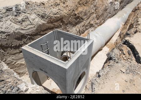 Verlegung der Abflussleitung aus Stahlbeton zwischen großen Wohngebieten. Neue Sanitäranlagen, Sturmabflusssysteme auf der Baustelle. Stockfoto
