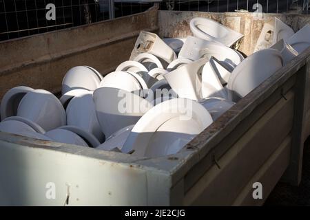 Entfernt Alte gebrauchte Keramik-Toilettenschüsseln liegen im Abfallbehälter in Heap für das Recycling. Bauabfall Stockfoto