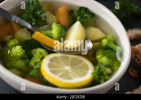 Vegetarische Gemüsesuppe mit Karotten, Brokkoli und Petersilie in einer leichten Schüssel, Nahaufnahme. Stockfoto