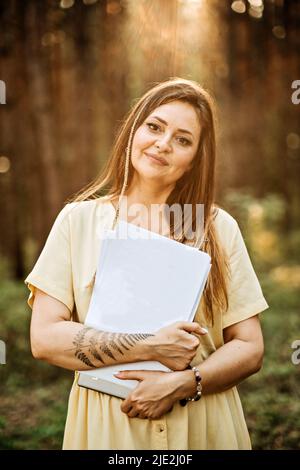 Modell im Freien, bei dem eine Frau ein leeres Papierdokument mit Platz für Kopien in der Hand hält. Stockfoto