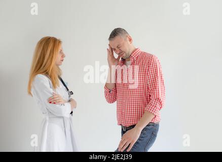Der Mann erzählt dem Mädchen vom Arzt über seine gesundheitlichen Beschwerden. Starke Kopfschmerzen Migräne. Stockfoto