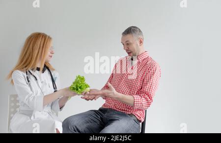 Eine Ernährungsberaterin bietet einem Mann frisches Gemüse, richtige und gesunde Ernährung in der Medizin Stockfoto