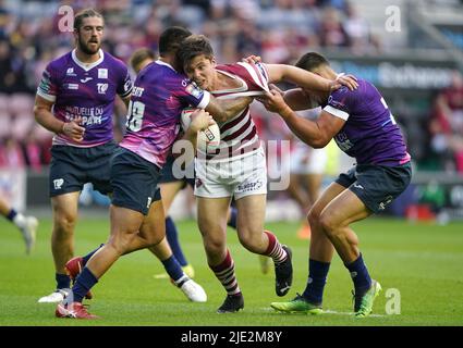 Wigan WarriorsÕ Ethan Havard wird von Toulouse OlympiqueÕs Lambert Belmas (rechts) und Nathan Peats während des Betfred Super League-Spiels im DW Stadium, Wigan, angegangen. Bilddatum: Freitag, 24. Juni 2022. Stockfoto