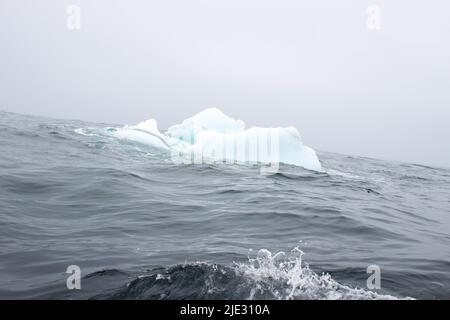 Welle krachend gegen kleine Eisberge, die im Meer schweben Stockfoto