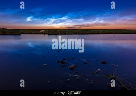 Nächtliche Wolken auch polare mesosphärische Wolken oder nächtliche Wolken reflektieren sich im Wasser Stockfoto