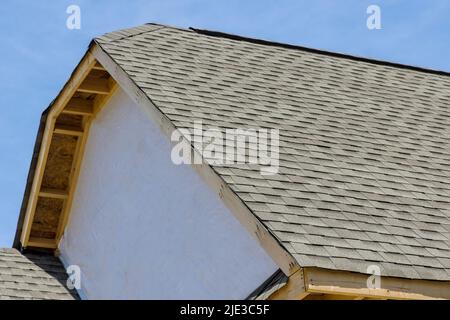 Dachabdichtung für ein neues Haus mit Asphaltschindeln in einer überdachten Ecke eines Gebäudes Stockfoto