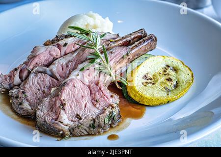 Mittelgroße Rare Lammkoteletts auf dem Teller mit gegrilltem Squash und Kartoffelpüree Stockfoto