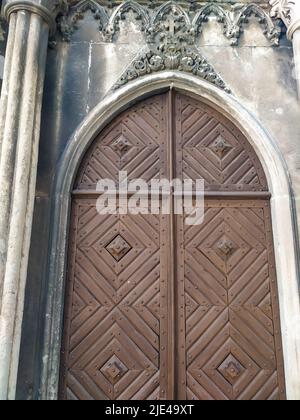 Zweiblättrige Holztür unter einem halbrunden Steinbogen Stockfoto