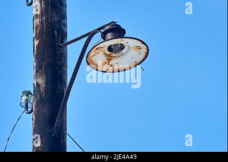 Eine alte Laterne hängt an einem Holzmast mit einer gebrochenen Glühbirne Stockfoto