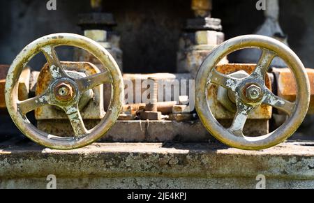 Vorderansicht Nahaufnahme von zwei gealterten rostigen Industrieventilrädern Stockfoto