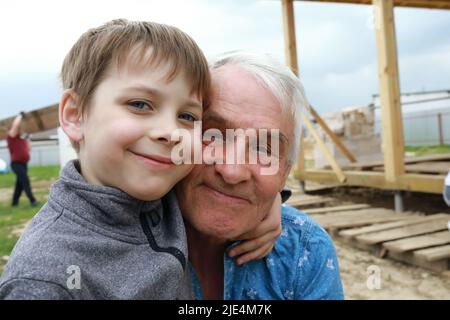 Enkel umarmt seinen Großvater im Hinterhof Stockfoto