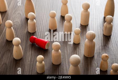 Holzfiguren auf einem Schreibtisch. Mobbing, Belästigkeit am Arbeitsplatz und Einsamkeit. Stockfoto