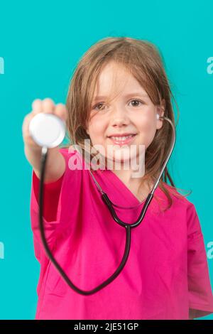 Ein 6-jähriges Mädchen ist gekleidet, als ein Arzt oder eine Krankenschwester den Kopf eines Stethoskops an die Kamera hält. Feminismus, MINT und Gesundheitskonzepte. Stockfoto