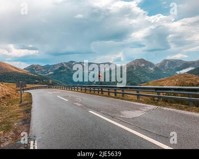 Serpentin in den Alpen. Eine leere Straße vor dem Hintergrund von Bergen und bewölktem Himmel. Europa Stockfoto