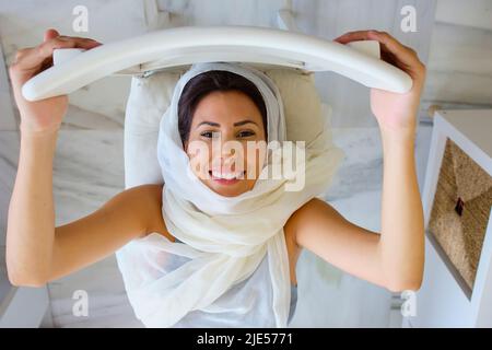 arabische junge Frau, die zu Hause mit Hijab Sport macht Stockfoto