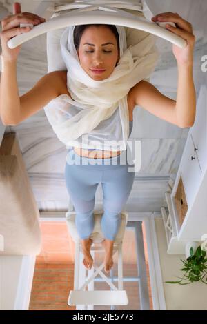 arabische junge Frau, die zu Hause mit Hijab Sport macht Stockfoto