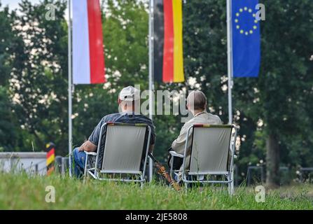 25. Juni 2022, Brandenburg, Neurüdnitz: Zwei Besucher warten auf die Eröffnung der Europabrücke, die eine Verbindung zwischen den beiden Ländern über die deutsch-polnische Grenzfluß oder schafft. Die ehemalige Eisenbahnbrücke zwischen der brandenburgischen Gemeinde Oderaue (Oderbruch) und dem polnischen Siekierki der westpommerschen Stadt Cedynia wurde am selben Tag für Fußgänger und Radfahrer geöffnet. Mietwagen können diese Verbindung nicht verwenden. Die Europabrücke bietet neben der zwischen Hohenwutzen und Osinow Dolny und der Fährverbindung zwischen Gozdowic eine weitere Möglichkeit, die oder zu überqueren Stockfoto