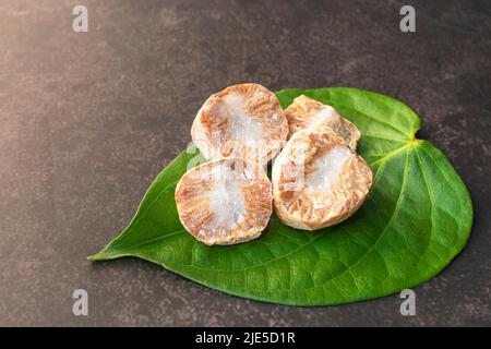 Frische Betelnuss oder Areca-Mutter mit Betelblatt isoliert auf dunklem Hintergrund. Stockfoto