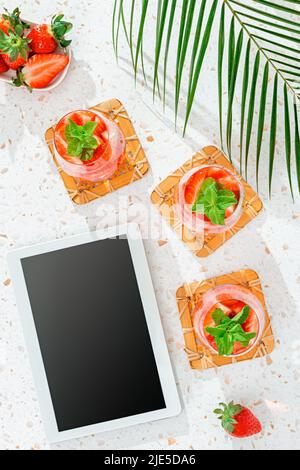 Sommer Minze und Erdbeere infundiert Wasser auf rosa Tischplatte mit langen Schatten, Draufsicht Stockfoto