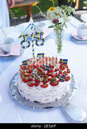 Die Feier des schwedischen Mittsommerabends am Freitag. Hier ist ein Erdbeerkuchen mit schwedischen Flaggen darauf. Stockfoto