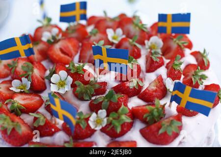 Die Feier des schwedischen Mittsommerabends am Freitag. Hier ist ein Erdbeerkuchen mit schwedischen Flaggen darauf. Stockfoto