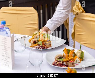 Die Kellnerin im Restaurant serviert einen Tisch mit Vorspeisen. Hochzeitstisch-Konzept Stockfoto