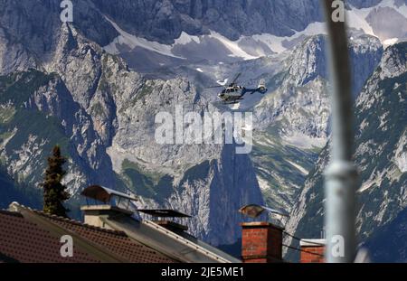 Garmisch Partenkirchen, Deutschland. 25.. Juni 2022. Ein Polizeihubschrauber fliegt über die Dächer vor den Bergen. Deutschland ist Gastgeber des Gipfels der wirtschaftlich starken Demokratien G7. Am ersten Tag des Gipfels werden die globale Wirtschaftslage, der Klimaschutz sowie die Außen- und Sicherheitspolitik mit den Sanktionen gegen Russland diskutiert. Quelle: Karl-Josef Hildenbrand/dpa/Alamy Live News Stockfoto