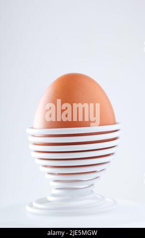 Ein gekochtes Ei in einer spiralförmigen Metallstütze, isoliert auf weißem Hintergrund Stockfoto