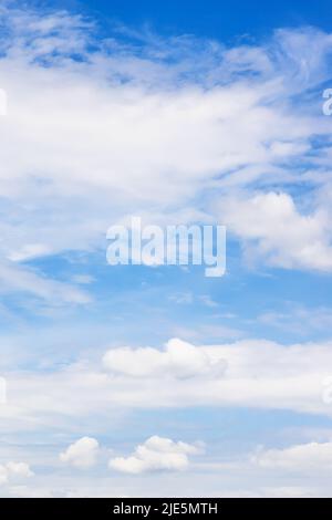 Vertikaler natürlicher Hintergrund - niedrige Zirrus- und Kumuluswolken am blauen Himmel an sonnigen Tagen Stockfoto