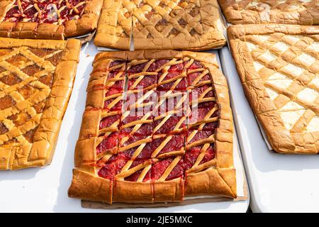 Große, flache, süße, offene Pie mit Himbeermarmelade auf dem Tisch schneiden Stockfoto