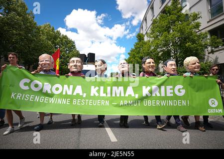 25. Juni 2022, Bayern, München: Aktivisten der Oxfam-Organisation tragen große Masken der G7 führenden Politiker (von links) Joe Biden, Präsident der USA, Mario Draghi, Premierminister von Italien, Emmanuel Macron, Präsident von Frankreich, Bundeskanzler Olaf Scholz (SPD), Justin Trudeau, Premierminister von Kanada, #Fumio Kishida, Premierminister von Japan, Boris Johnson, Premierminister von Großbritannien, während einer Demonstration der G7 Kritiker für einen besseren Klima- und Artenschutz sowie gegen Hunger und Armut. Fünfzehn globalisierungskritische Verbände haben zur Demonstration in München aufgerufen. G Stockfoto