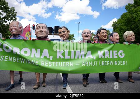 25. Juni 2022, Bayern, München: Aktivisten der Oxfam-Organisation tragen große Masken der G7 führenden Politiker (von links) Joe Biden, Präsident der USA, Mario Draghi, Premierminister von Italien, Emmanuel Macron, Präsident von Frankreich, Bundeskanzler Olaf Scholz (SPD), Justin Trudeau, Premierminister von Kanada, #Fumio Kishida, Premierminister von Japan, Boris Johnson, Premierminister von Großbritannien, während einer Demonstration der G7 Kritiker für einen besseren Klima- und Artenschutz sowie gegen Hunger und Armut. Fünfzehn globalisierungskritische Verbände haben zur Demonstration in München aufgerufen. G Stockfoto
