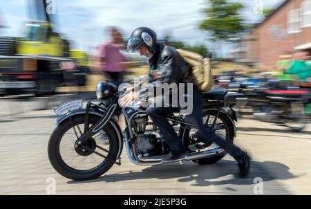 Wismar, Deutschland. 25.. Juni 2022. Ein Teilnehmer schiebt seinen historischen Motor vor dem Start bei der Oldtimer-Rallye 7. vor dem Phantechnikum. (Langzeitaufnahme) bei der Oldtimer-Rallye gehen historische Motorräder und Autos auf die Rennstrecke, um der Geschichte der Mobilität zu gedenken. Quelle: Jens Büttner/dpa/Alamy Live News Stockfoto