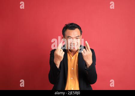 Der asiatische Mann mittleren Alters, der auf dem roten Hintergrund steht. Stockfoto