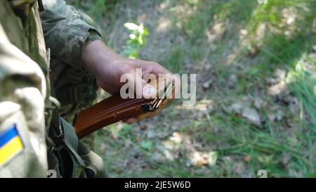 Ukrainischer Soldat lädt Maschinengewehr Magazin mit Patronen Stockfoto