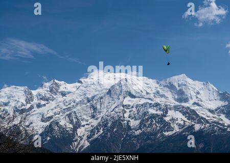 Paragliding über den Bergen und einer Stadt in den Alpen in Frankreich Stockfoto