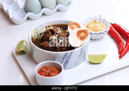 Rawon, Schwarzes Suppengericht Mit Indonesischem Rindfleisch. Schwarze Farbe aus Keluak Nuss als Hauptgewürze, verleiht der Suppe dunkle Farbe und nussigen Geschmack. Stockfoto