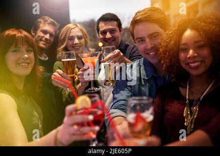 Lchaim. Porträt einer Gruppe von Menschen, die in einem Nachtclub mit ihren Getränken toasten. Stockfoto