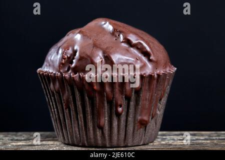 Schokoladen-Cupcake in schwarzer Papierverpackung, schokoladengetränkten Cupcake mit Schokoladengeschmack auf einem Holztisch Stockfoto
